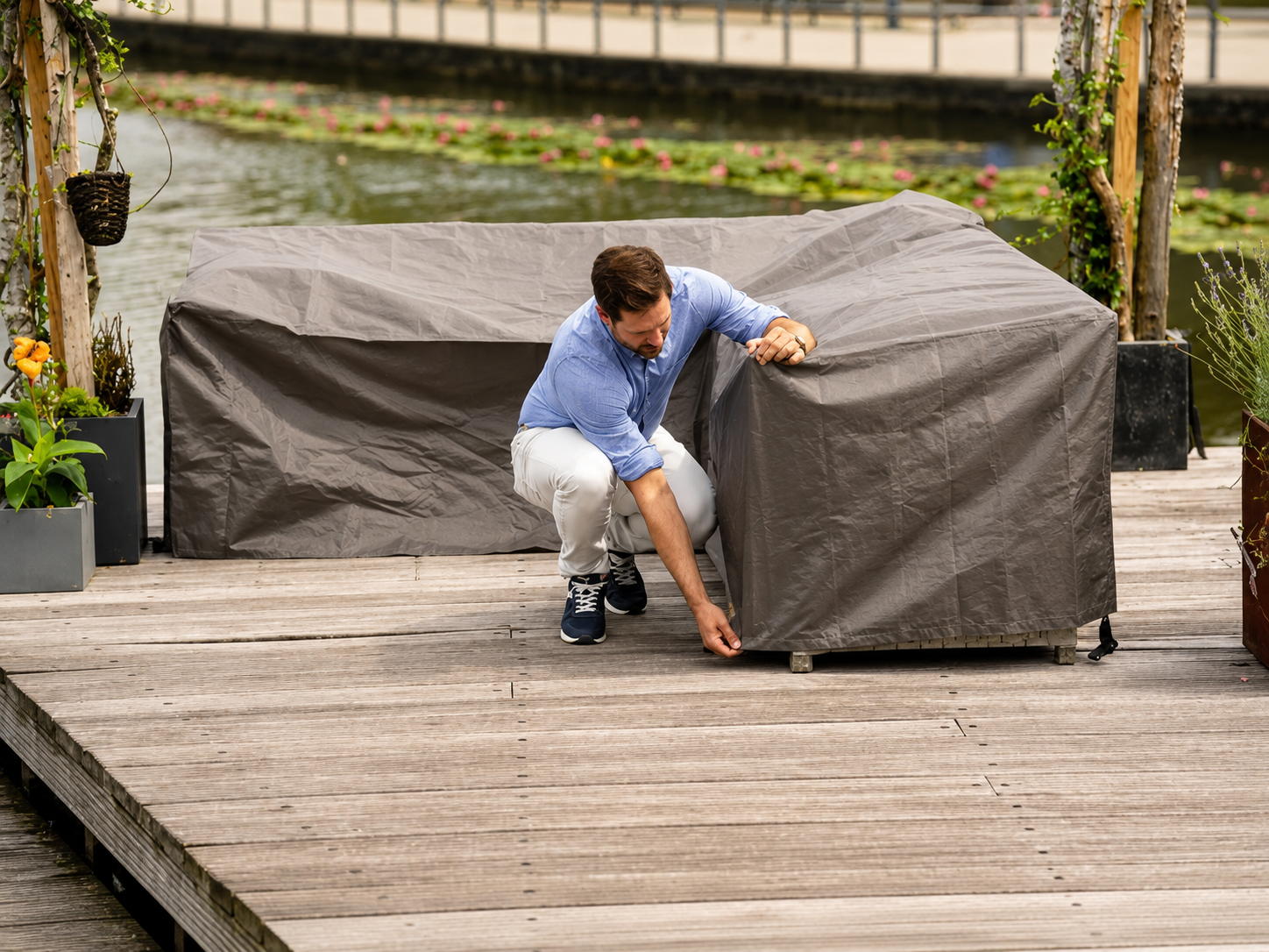 Beschermhoes Winza Loungeset L-vorm antraciet, sfeerbeeld met persoon op houten terras
