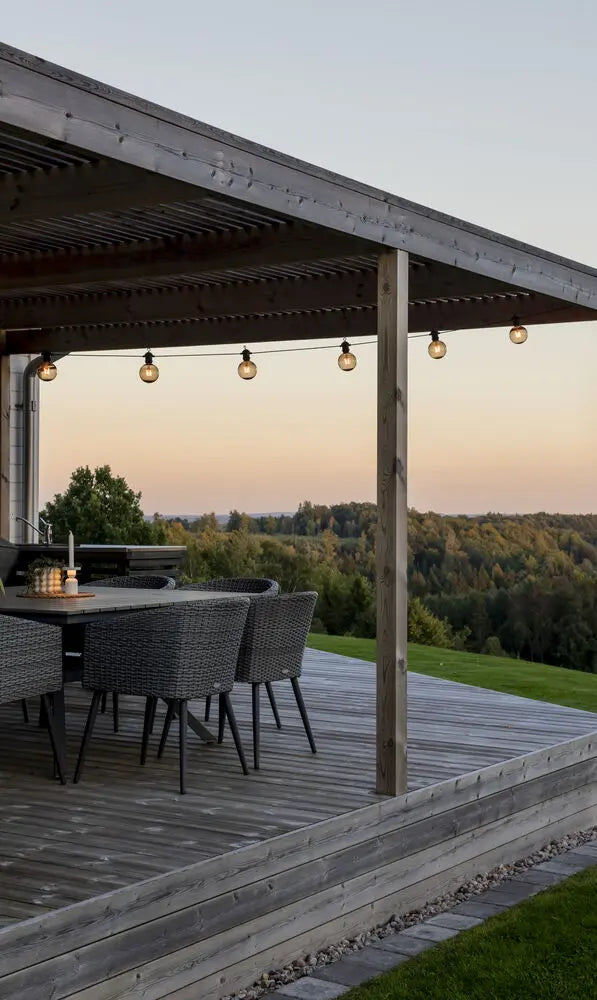 Konstsmide lichtsnoer opgehangen aan een veranda, verlicht bij zonsondergang