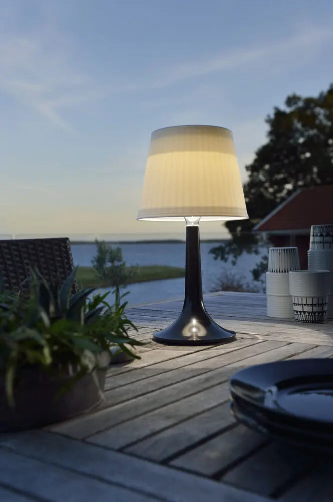 Konstsmide Assisi tafellamp op een terras bij zonsondergang, ander perspectief met planten
