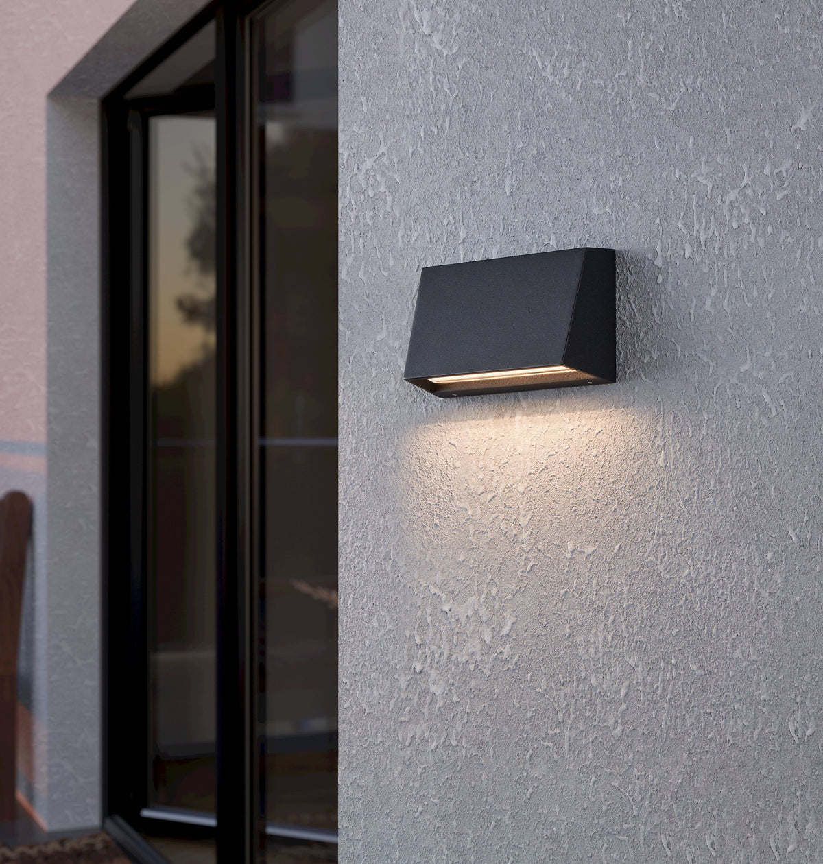 EGLO Spongano wandlamp gemonteerd aan een gevel naast een deur, verlicht en in gebruik