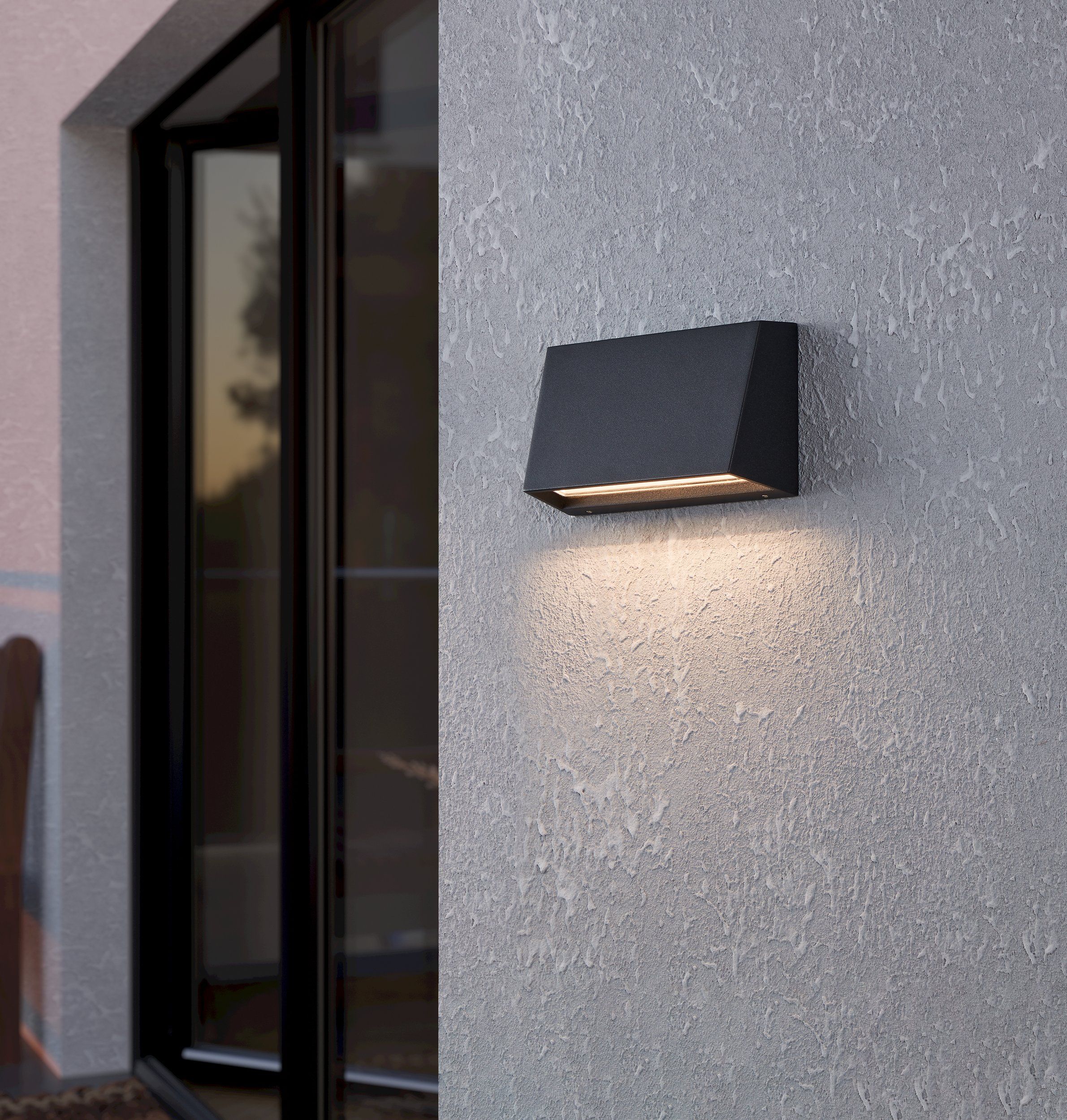EGLO Spongano wandlamp gemonteerd aan een gevel naast een deur, verlicht en in gebruik