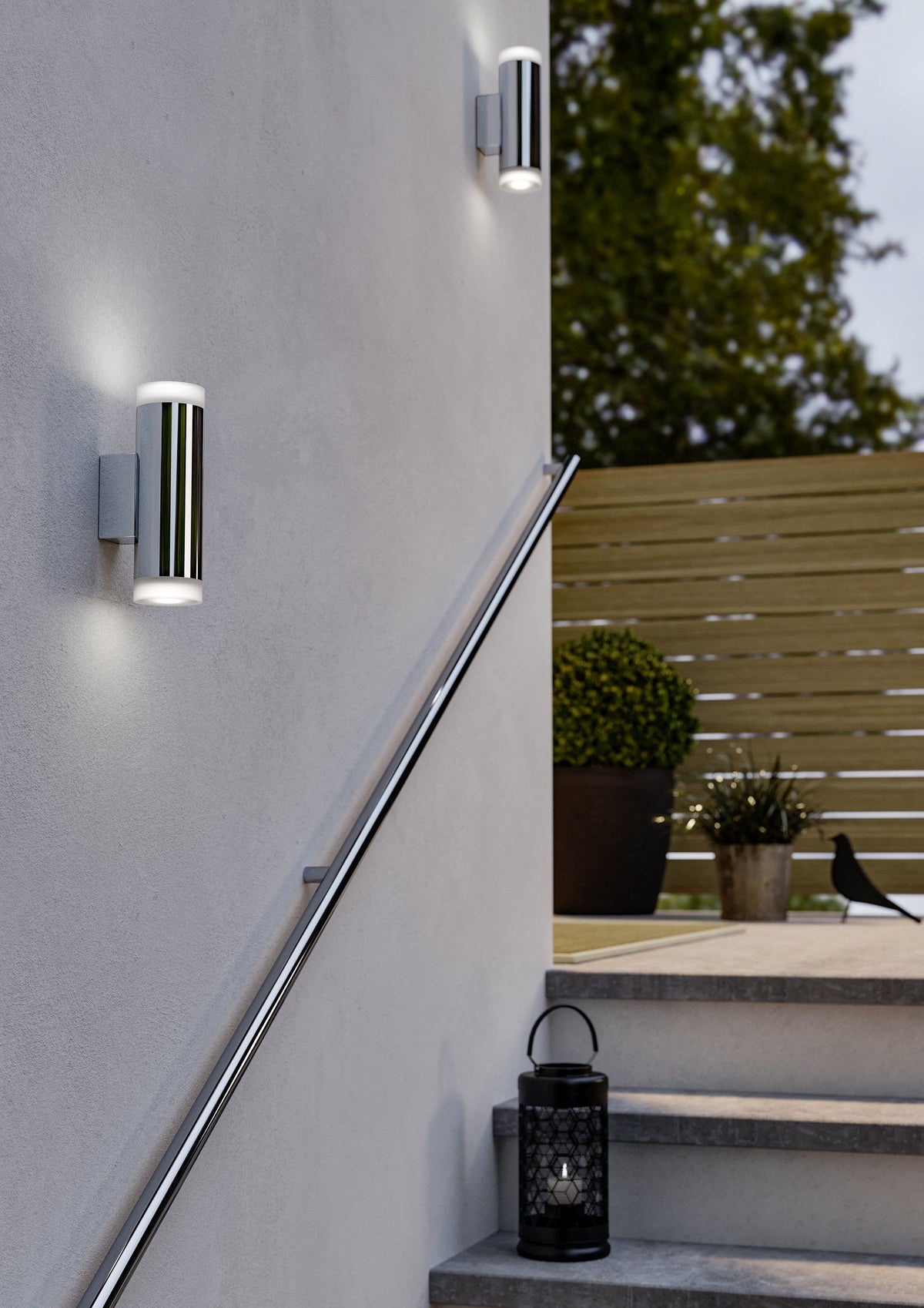 EGLO Riga-LED wandlamp gemonteerd aan een gevel naast een buitentrap, verlicht bij avondlicht