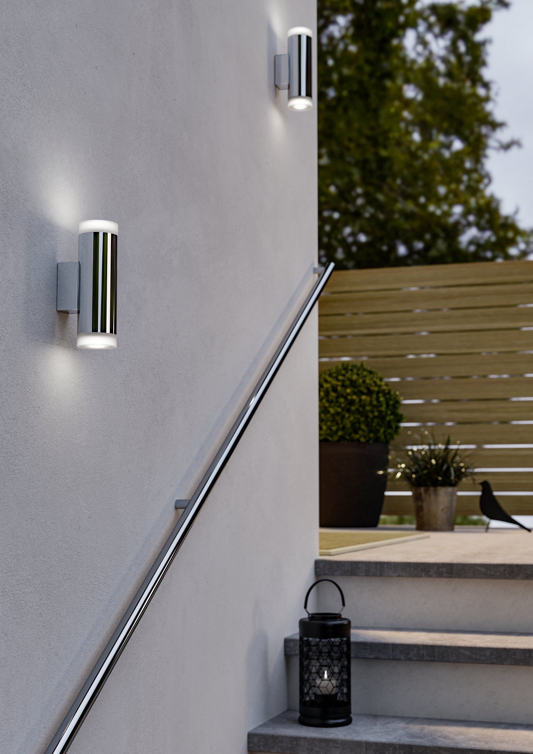 EGLO Riga-LED wandlamp gemonteerd aan een gevel naast een buitentrap, verlicht bij avondlicht