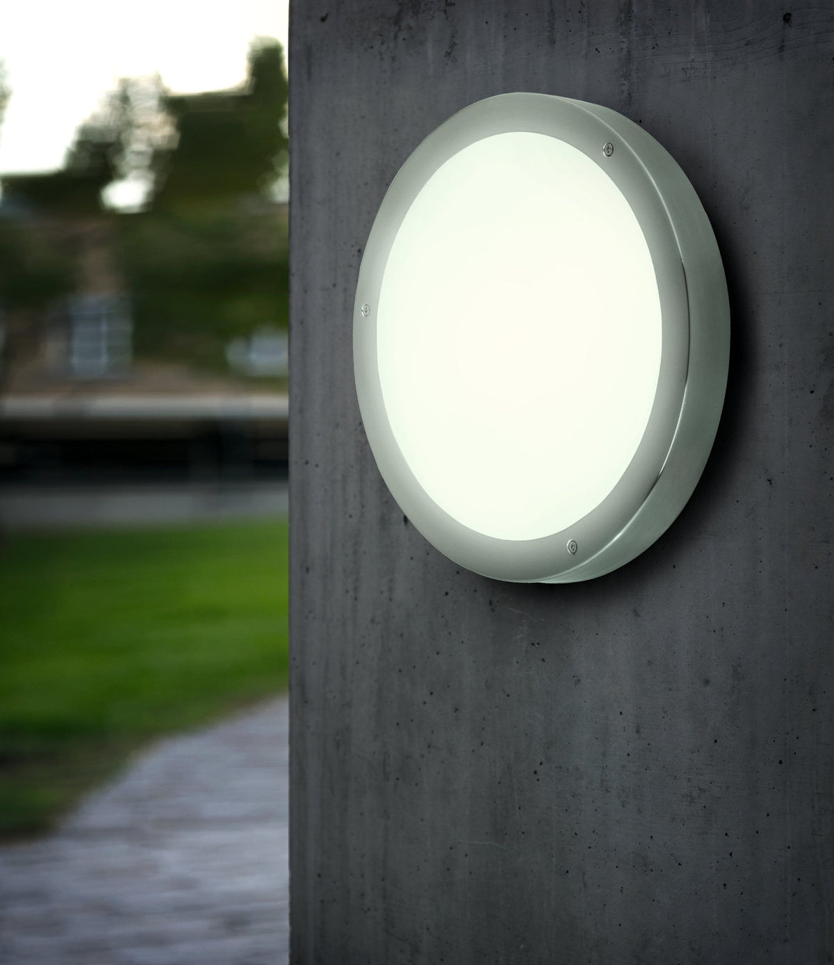 EGLO Vento 1 wandlamp gemonteerd aan een gevel naast een tuinpad, verlicht bij avondlicht
