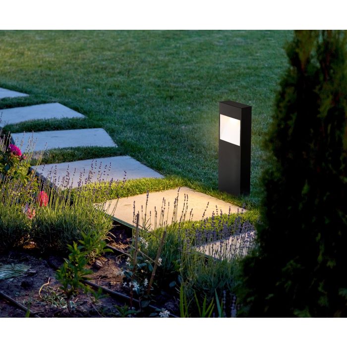 EGLO Manfria sokkellamp langs een tuinpad met stapstenen, verlicht bij avondlicht