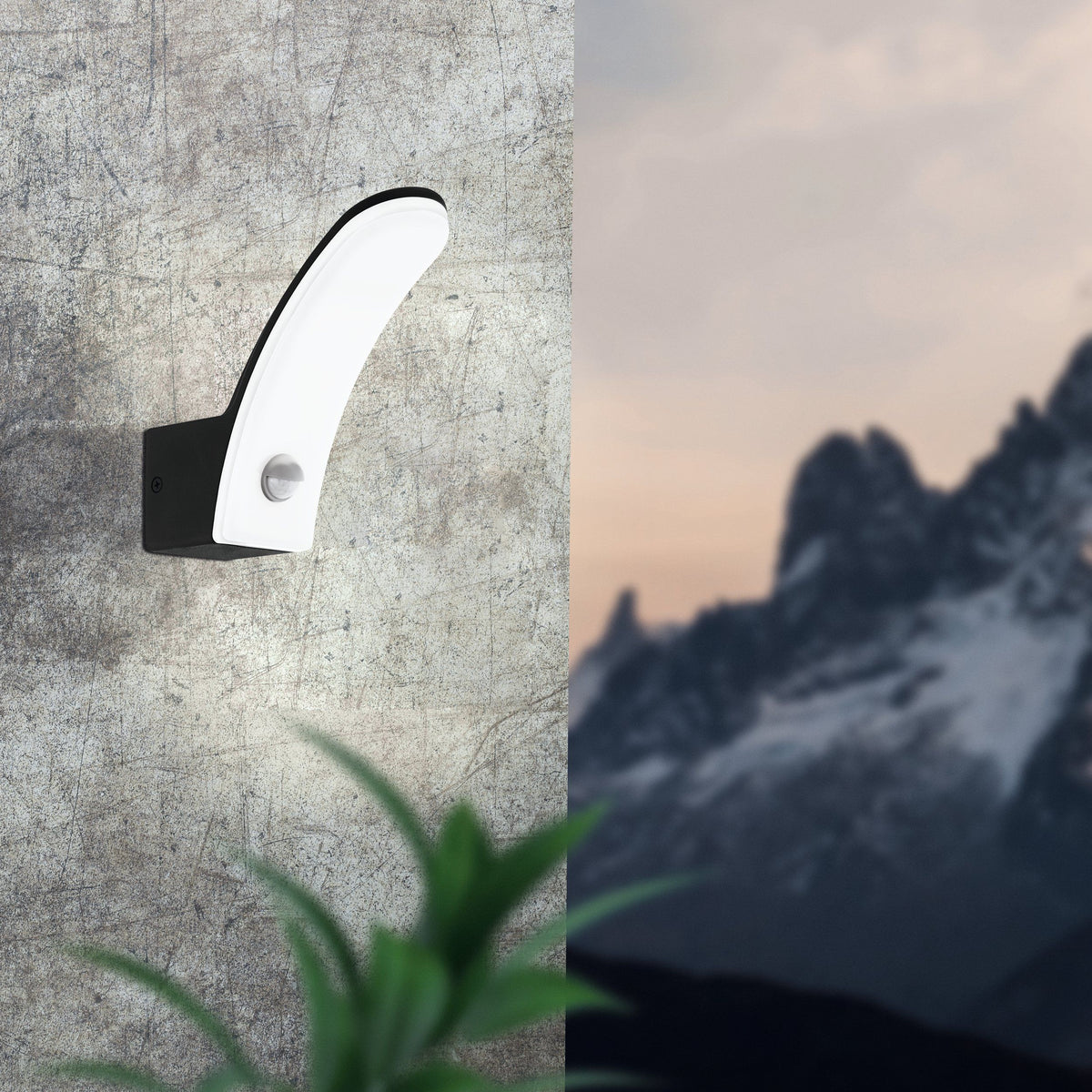 EGLO Fiumicino wandlamp gemonteerd tegen een stenen muur, met bergzicht op de achtergrond