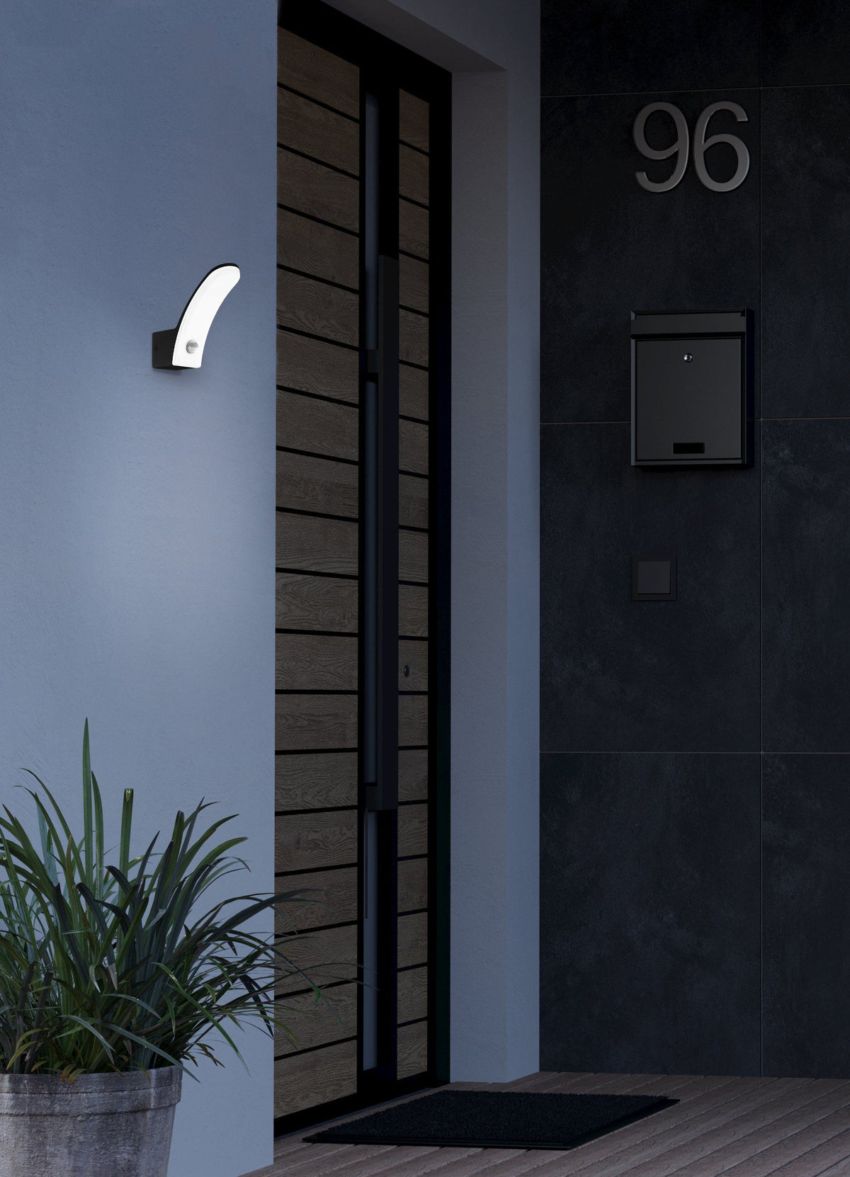 EGLO Fiumicino wandlamp gemonteerd naast een voordeur, verlicht bij avondlicht