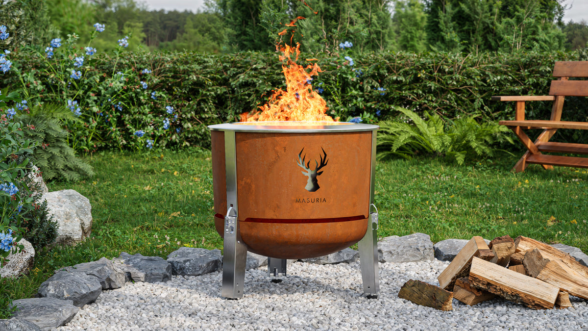 Alpha 600 Corten rookloze vuurkorf in tuinomgeving overdag met vlam