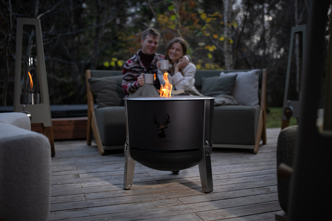 Stel geniet bij de Alpha 600 Black vuurkorf in avondsfeer in de tuin