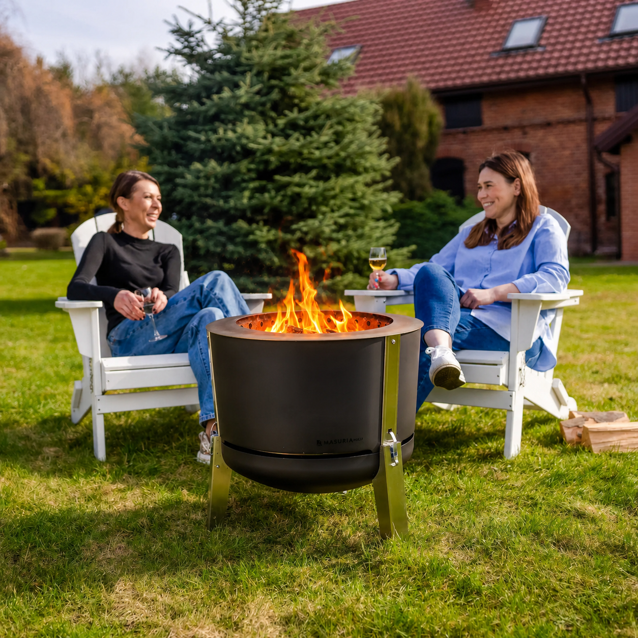 Stel geniet buiten bij de Alpha 600 Black vuurkorf in witte tuinstoelen