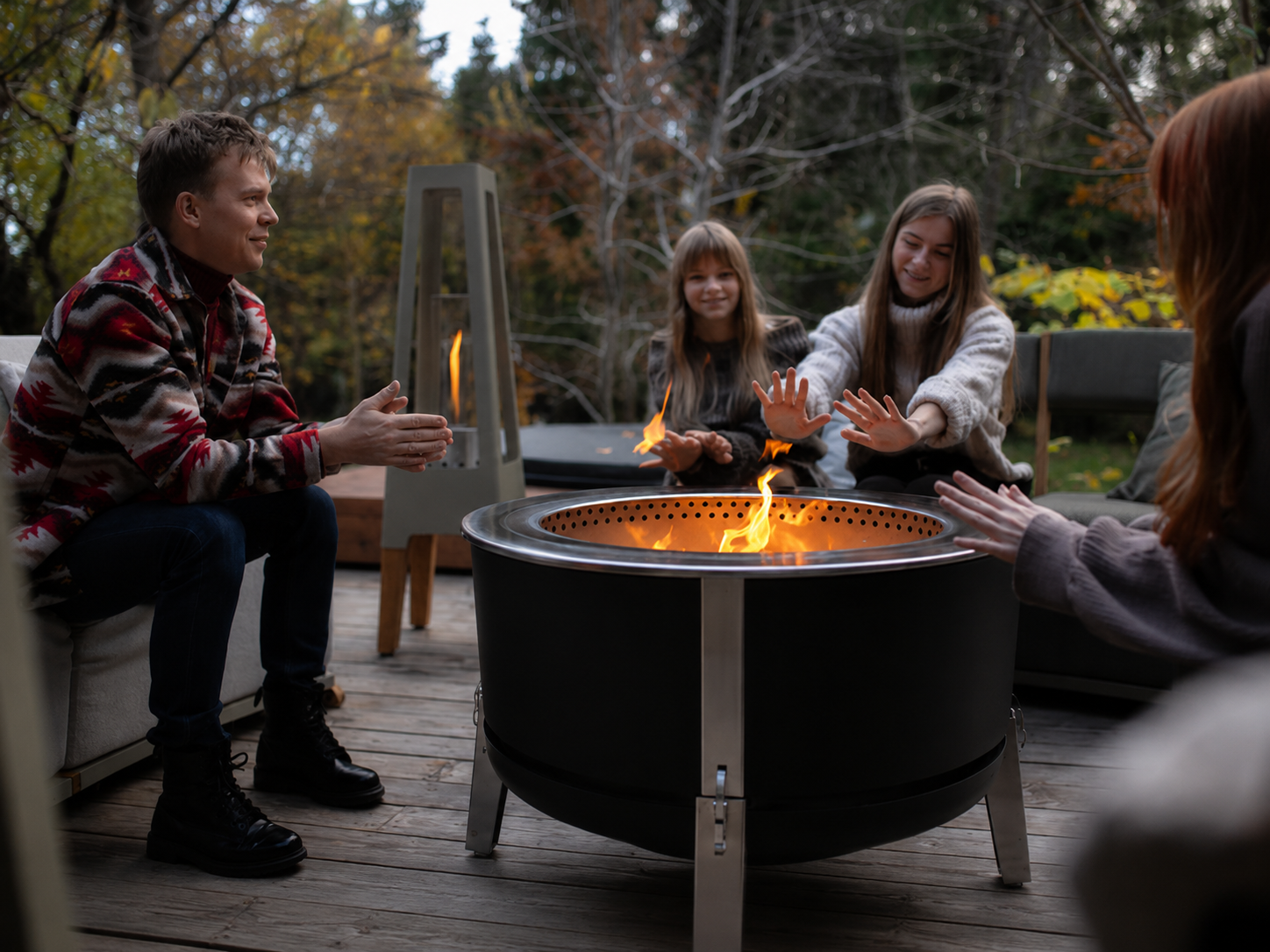 Groep mensen geniet 's avonds bij de Alpha 600 Black vuurkorf met plancha