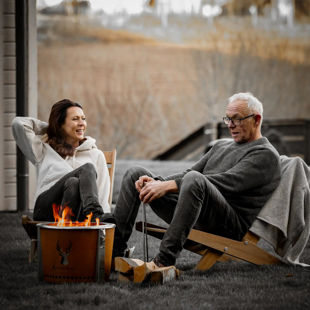 Stel zit 's avonds buiten bij de Alpha Camp Corten rookloze vuurkorf in stoelen
