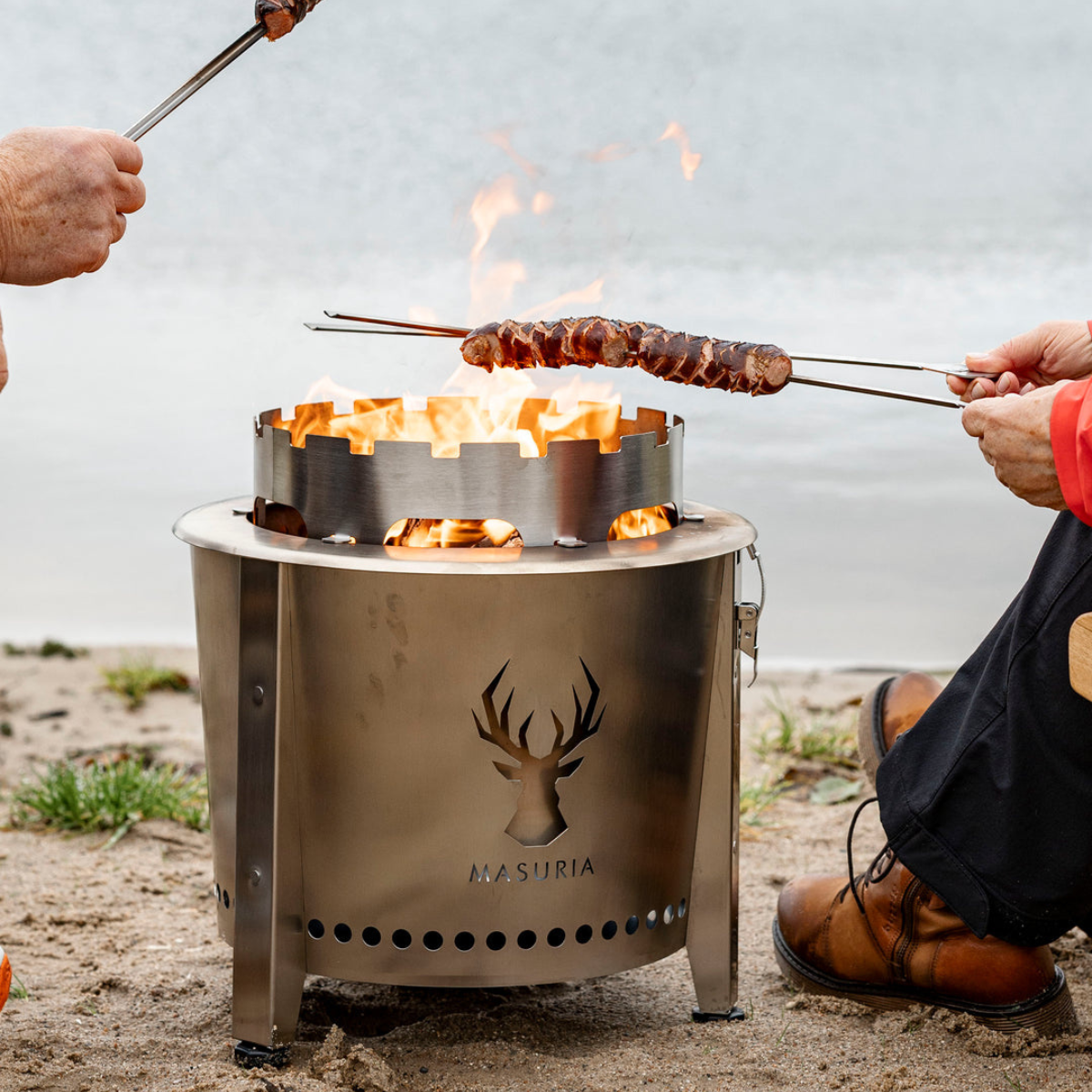 Persoon roostert marshmallows boven de Alpha Camp Zilver vuurkorf aan het meer