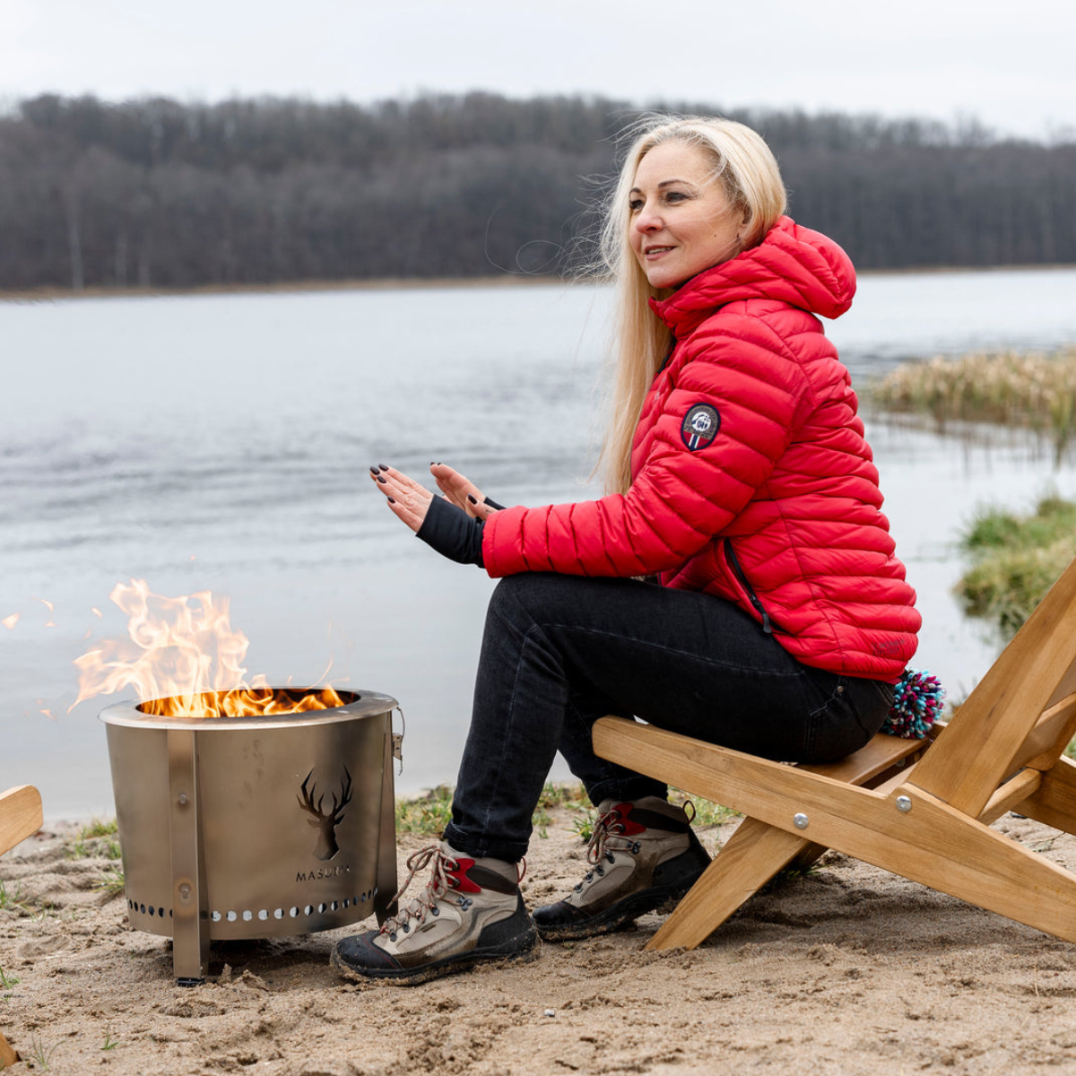 Vrouw in rode jas geniet buiten bij de Alpha Camp Zilver rookloze vuurkorf