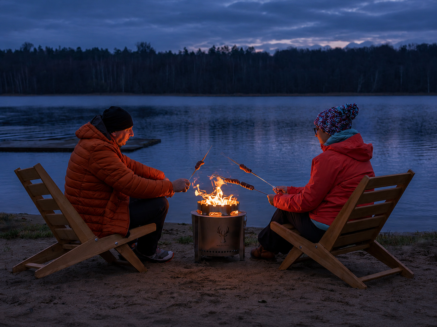 Twee mensen genieten 's avonds bij het meer bij de Alpha Camp Zilver vuurkorf