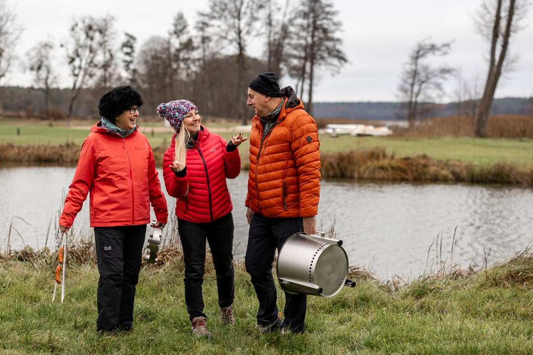 Groep mensen buiten draagt de Alpha Camp Zilver vuurkorf mee op avontuur