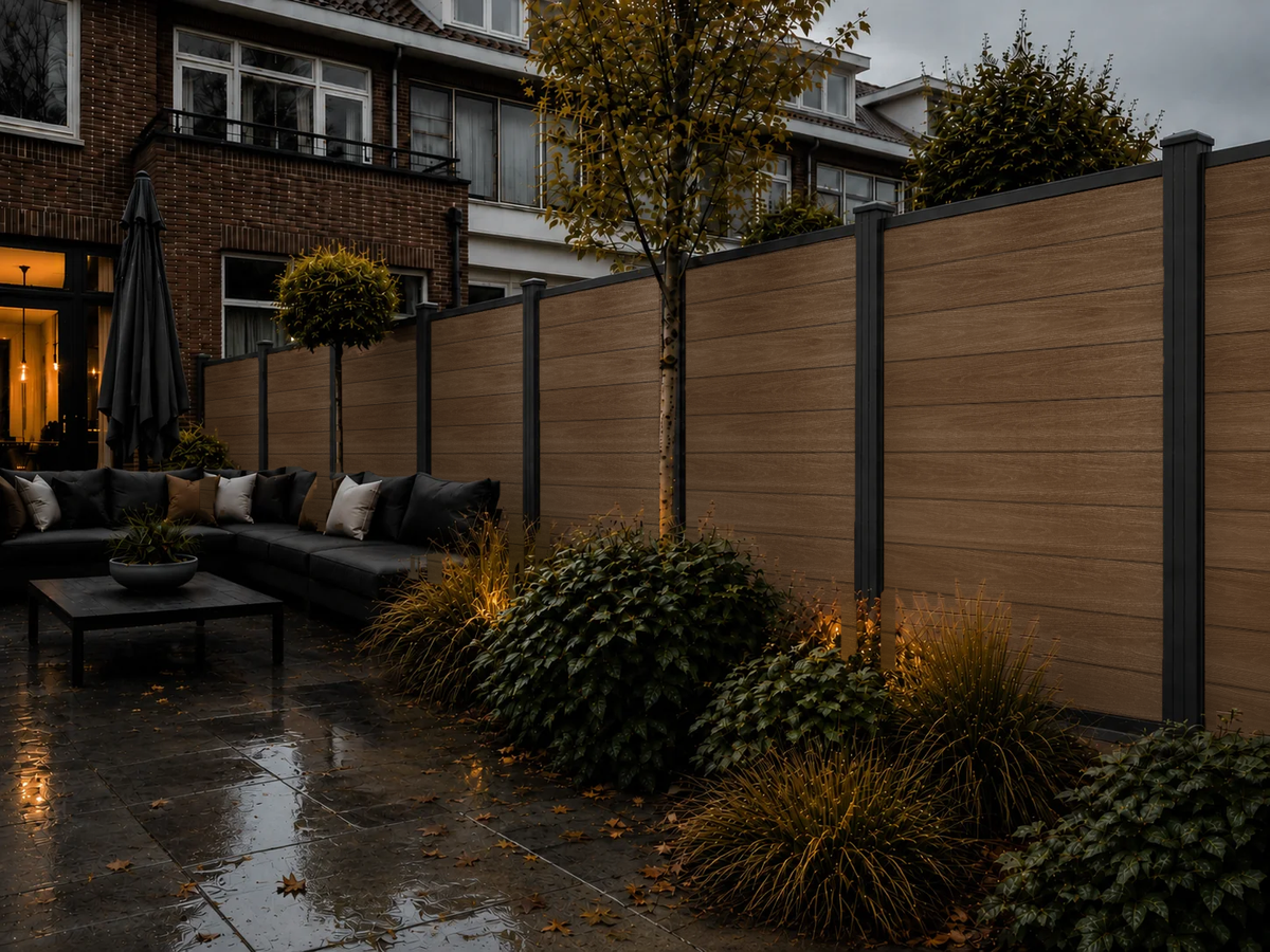 Teakkleurige composiet schutting in de tuin bij avondverlichting