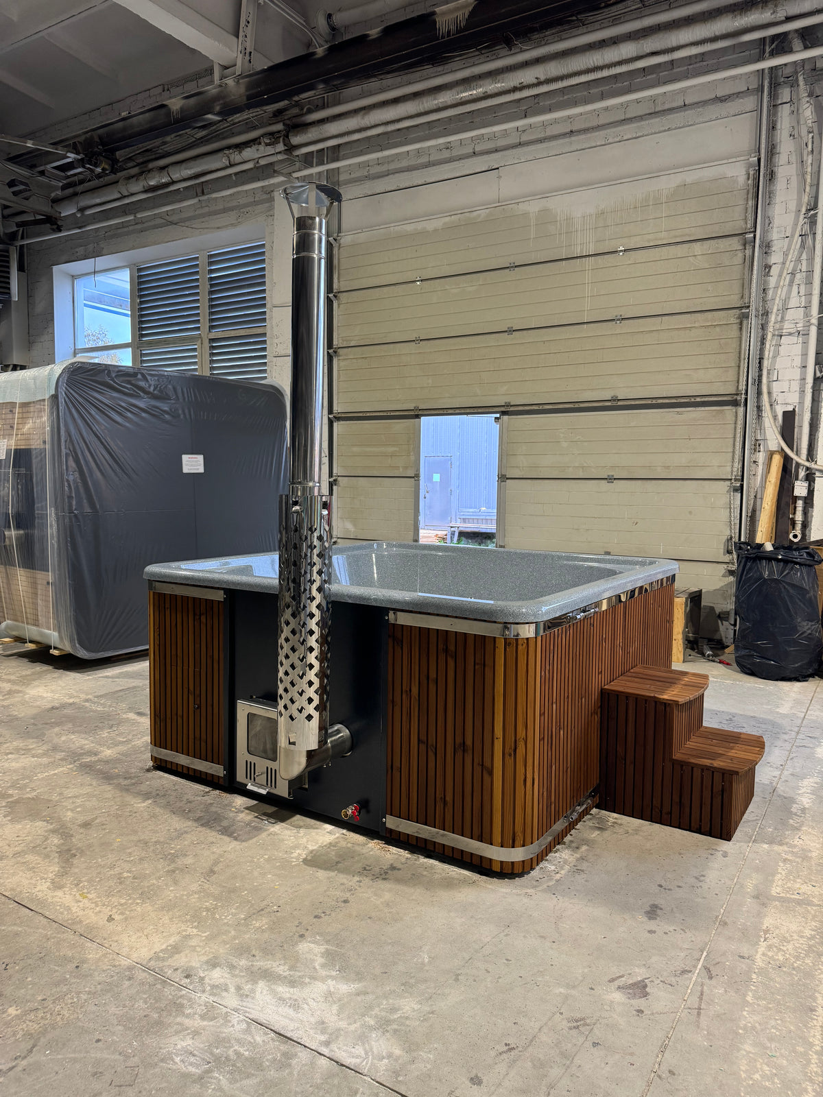Zijaanzicht van de Quadro Hot Tub met rookpijp in een showroom